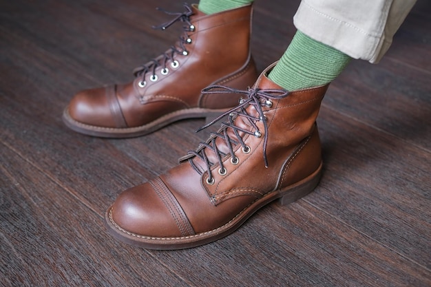 feet of man in green socks in stylish baroque leather boots on a wooden floor close-up