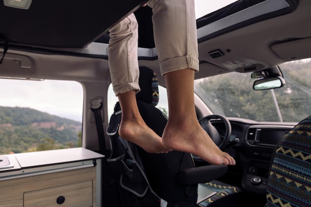 Feet of a man sitting on the roof tent of his van