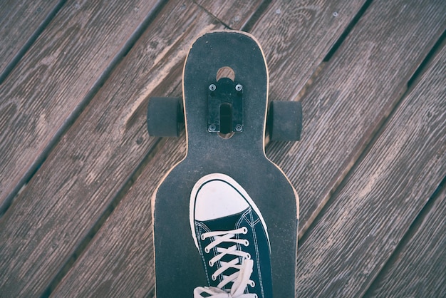 Piedi dell'uomo in scarpe da ginnastica su un longboard alla sera