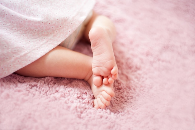 Feet of newborn baby girl on pinkblanket fingers on the foot maternal care love and family hugs tenderness newborn baby girl legs