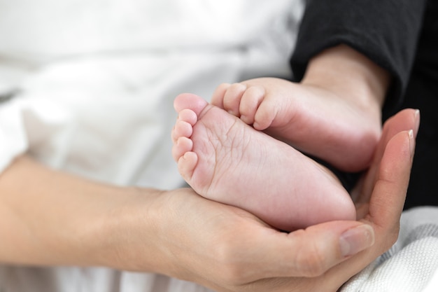 Feet of a newborn baby in the hand of mom. Happy family concept.