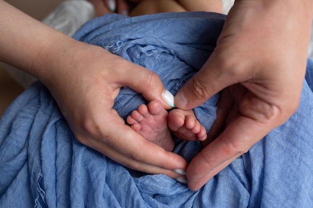 Foto piedi di un neonato nelle mani dei genitori gambe su sfondo blu piedi del bambino