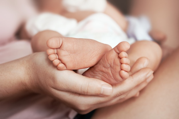 Photo feet of newborn baby on mothers palm