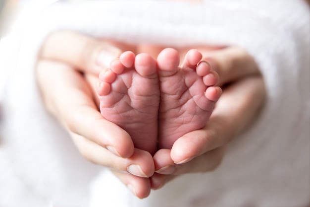 Feet newborn baby in a white cloth in my mothers hands