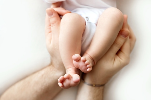 Piedi di un neonato nelle mani di un padre, genitore. fotografia in studio, sfondo bianco. concetto di famiglia felice. foto di alta qualità