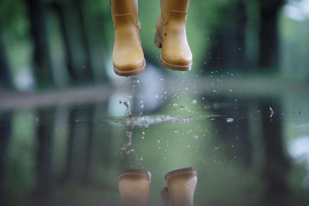 feet in rubber boots rain puddle city