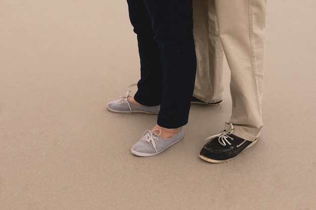 feet of senior couple standing at the beach