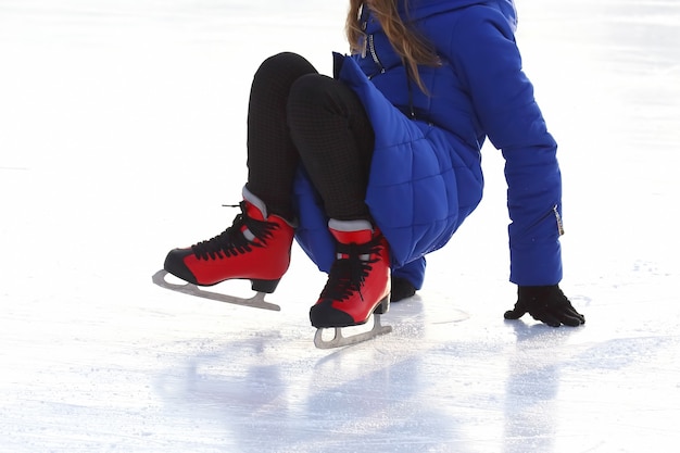 Feet in skates of a fallen man on an ice rink