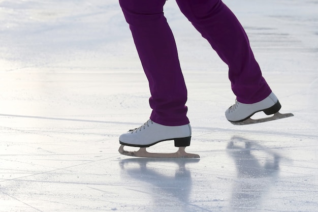 Feet on the skates of a person rolling on the ice rink. Sports and winter holidays