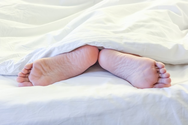 Feet of sleeping woman in white bed room