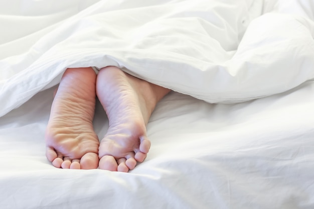 Feet of sleeping woman in white bed room