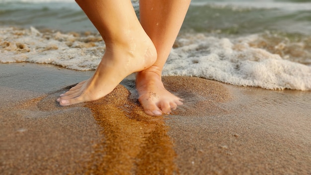 Piedi piccolo bambino sulla sabbia con onda d'acqua della spiaggia del mare. vacanze estive