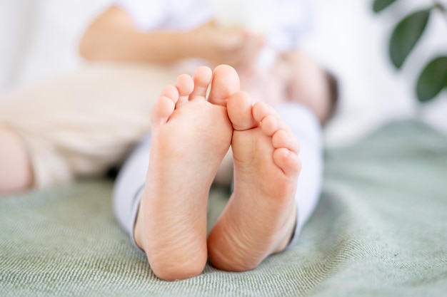 The feet of a small child on a green bed the heels of a baby closeup