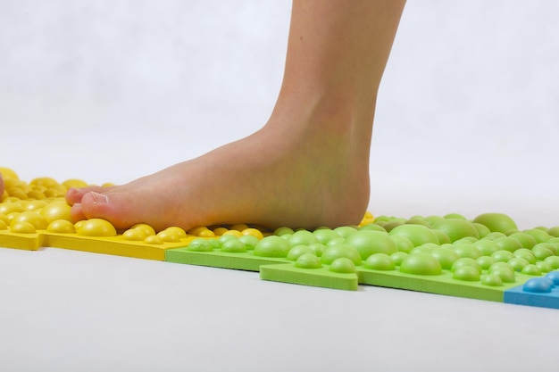 The feet of small children on a orthopaedic mat. White background. Free space for a text.