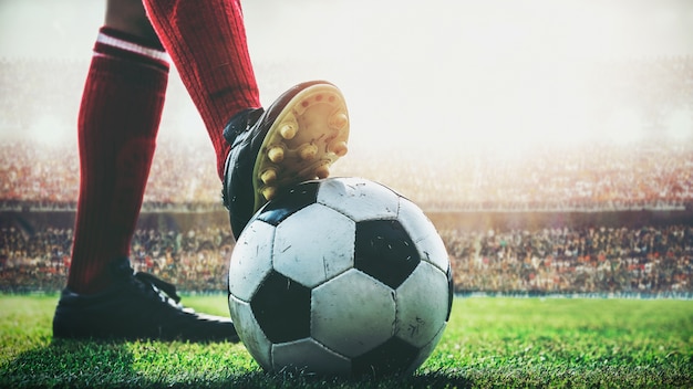 Photo feet of soccer player tread on soccer ball for kick-off in the stadium