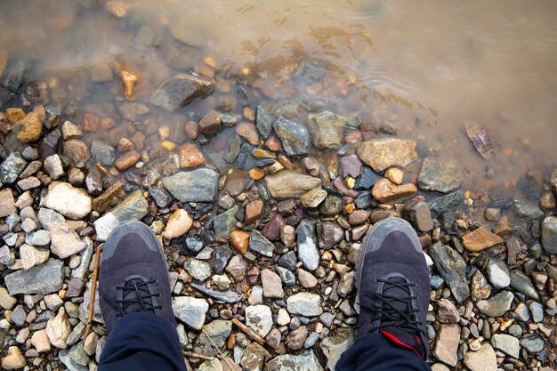 Foto i piedi del viaggiatore sulle rive del fiume la riva rocciosa della fauna selvatica