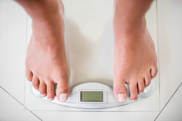 Feet of woman on weighting scale at home