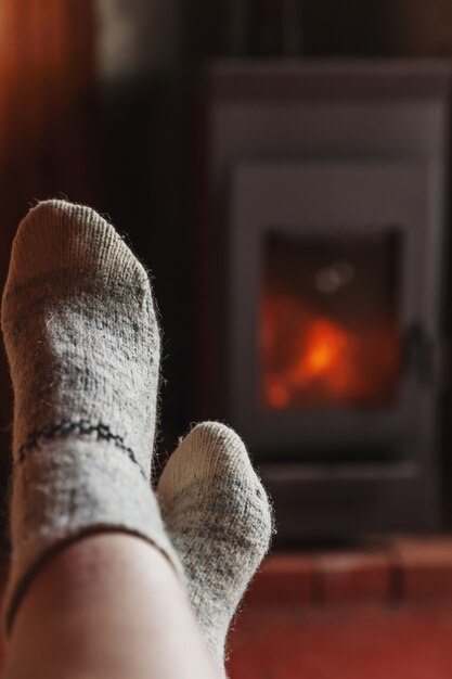 Feet in wool socks at fireplace background