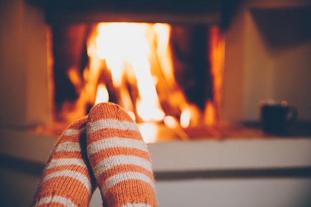 Feet in wool striped socks by the fireplace Relaxing at Christmas fireplace on winter holiday evening