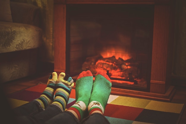 Feet in woollen socks by the Christmas fireplace. Close up on feet. Winter and Christmas holidays concept.