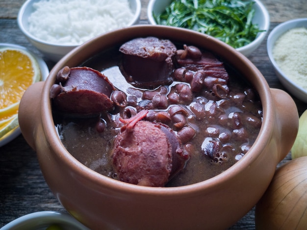 Feijoada in een keramische kom, traditioneel Braziliaans eten op een houten ondergrond.