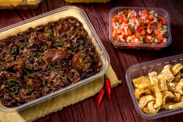 Feijoada in lunch box, food delivery,  Typical Brazilian dish based on black beans and pork .