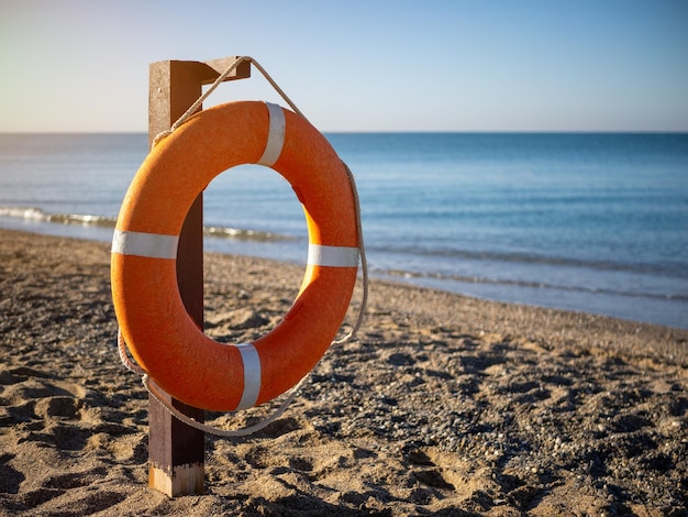 Foto fel oranje reddingsboei op een zandstrand op een zonnige zomerdag