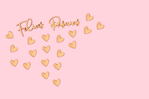 ピンクの背景に手書きの木製の手紙と木製の心のFelicesPascuasの単語