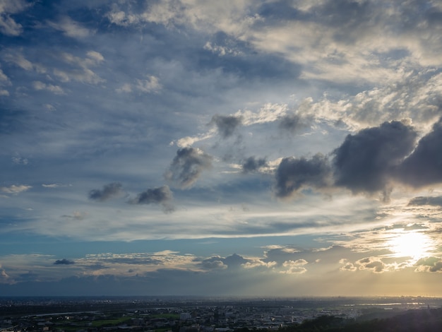 Felle zon in blauwe lucht met donkere wolken