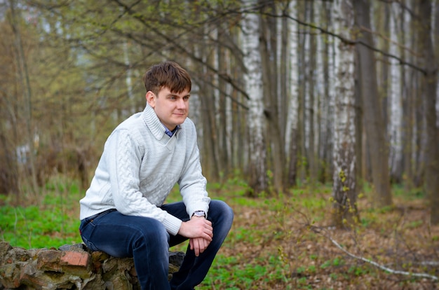 Fellow a man sits on a stone in-field and looks