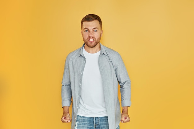 Fells anger Young man in casual clothes standing indoors in the studio