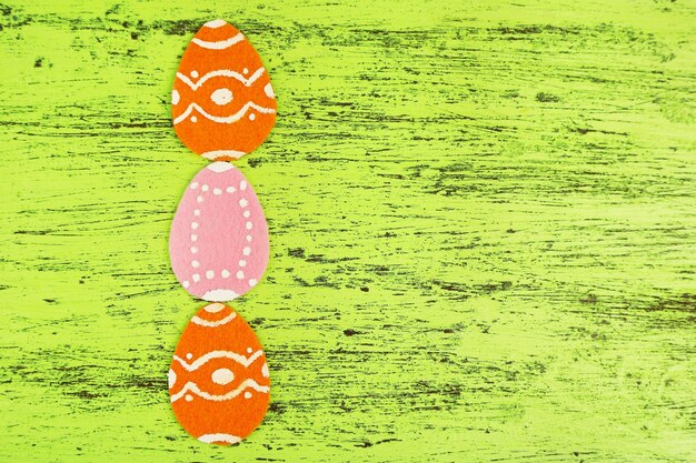 Uova di pasqua in feltro su sfondo di legno colorato