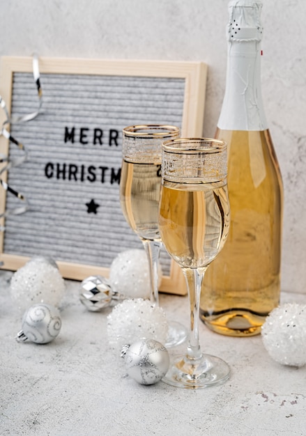 Felt letter board Merry Christmas on a table with champagne glasses and bottle