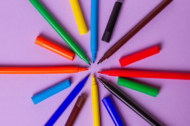 Felttip pens without caps of different colors on a purple background Arranged in a circle