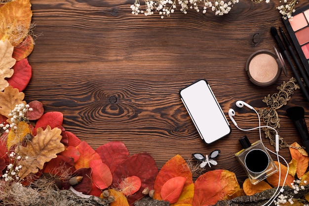 Female accessories Set. autumn leaves, smartphone and earphones on wood