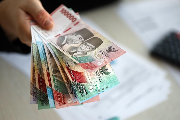 여성 회계사 손은 많은 인도네시아 루피아 돈 지폐의 새로운 시리즈를 어줍니다.
