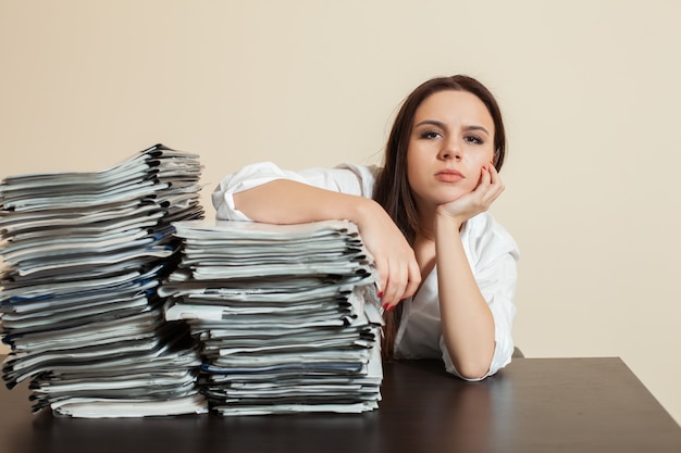 Female accountant hugs big stacks of documents