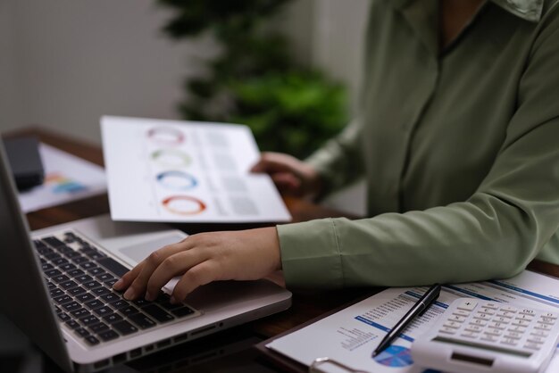 Female accountant reading document to analysis about accounting finance of business to typing data