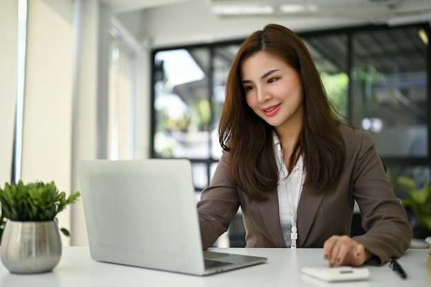 A female accountant using her laptop computer and working at her desk in her office