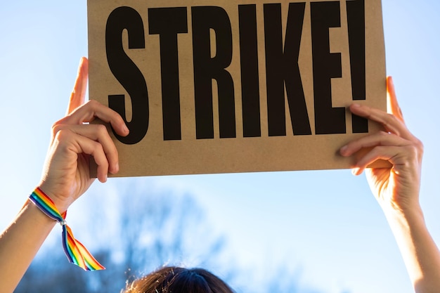 A female activist holding a sign with the slogan of the hollywood actors and writers strike with the blue sky in the background