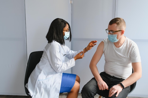 Photo female african doctor injecting a patient