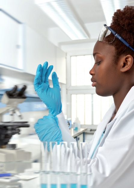 Female african scientist, doctor or intern puts on her protective gloves on