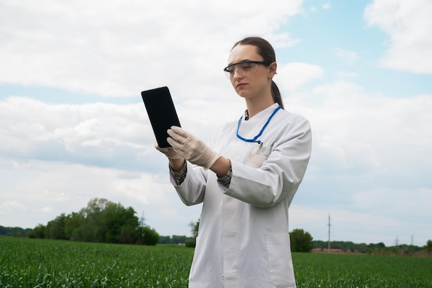 a female agronomist in a white coat checks the growth of plants in the field