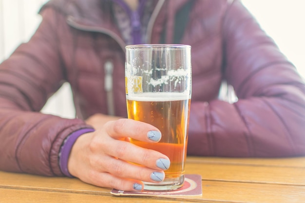 Foto alcolismo femminile un bicchiere di birra sul tavolo davanti a una donna