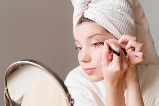 Female applying eyeliner in mirror