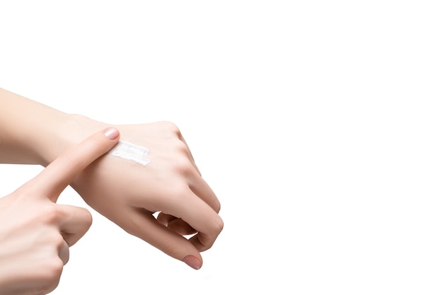 Female applying white lotion on her hand. Beautiful young woman hand with cream, isolated on white background.