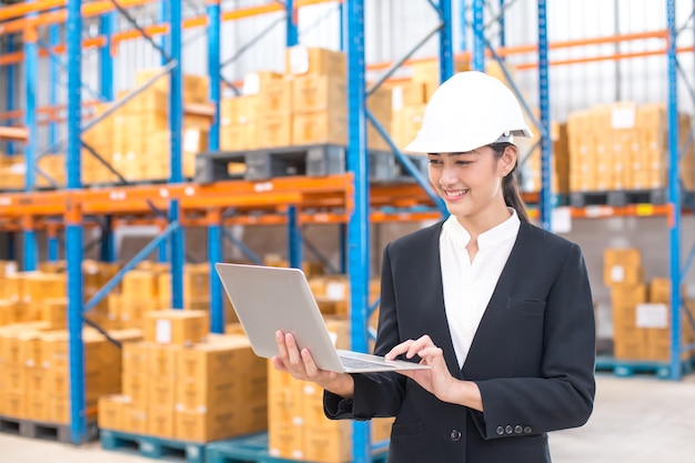 Female architect holding laptop with smiling at warehouse. People working concept.