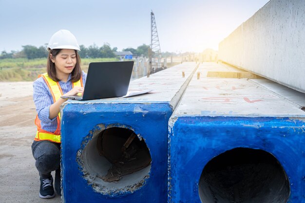 Female architect leader working with laptop and blueprints at construction site or building site.