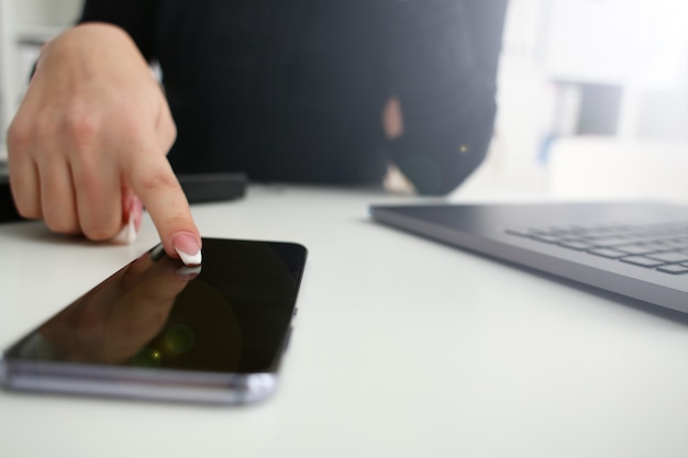 Telefono femminile della stretta del braccio al primo piano del posto di lavoro.