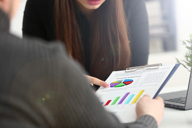 Female arm holding silver pen point in financial graph